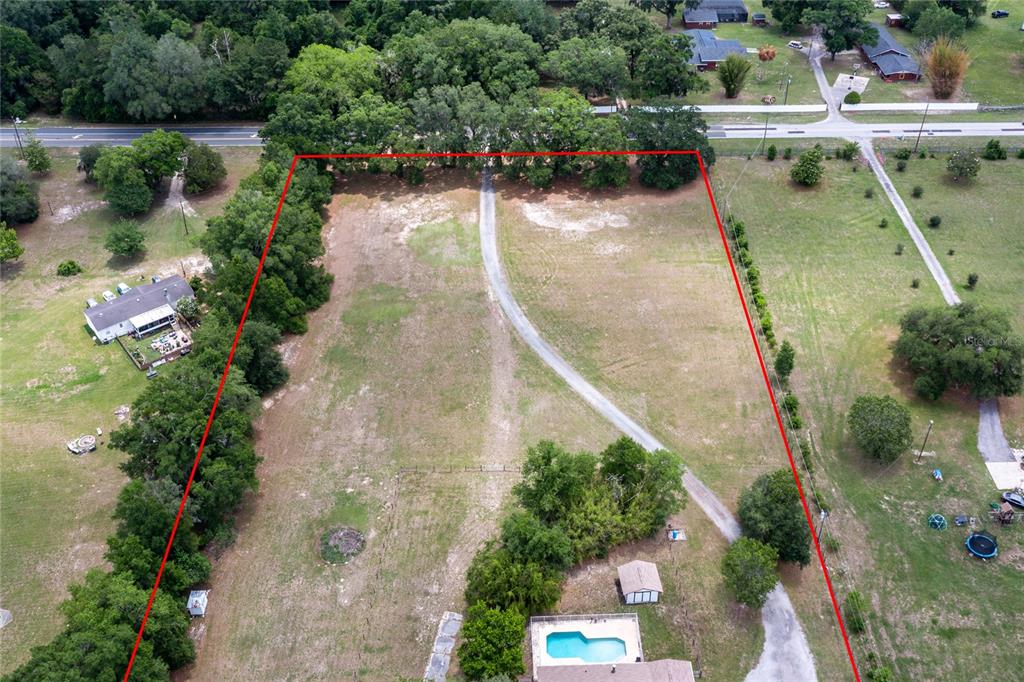 An aerial view shows a large, grassy lot outlined in red with a central driveway — 7416 SW 75TH STREET, GAINESVILLE, FL