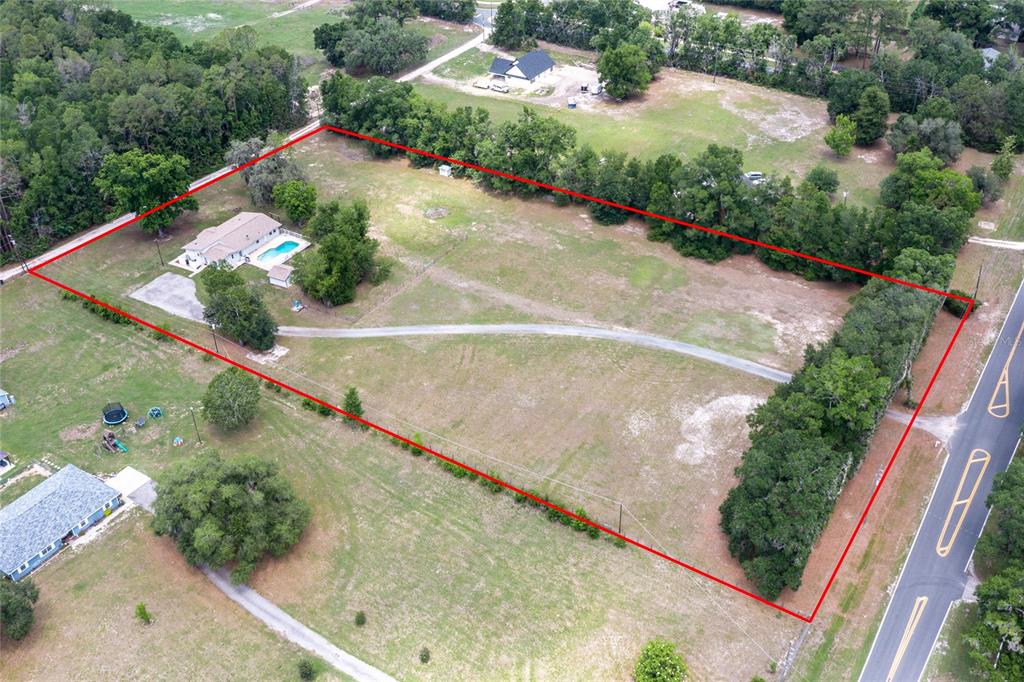 An aerial view shows a house with a pool on a large, fenced-in grassy lot — 7416 SW 75TH STREET, GAINESVILLE, FL