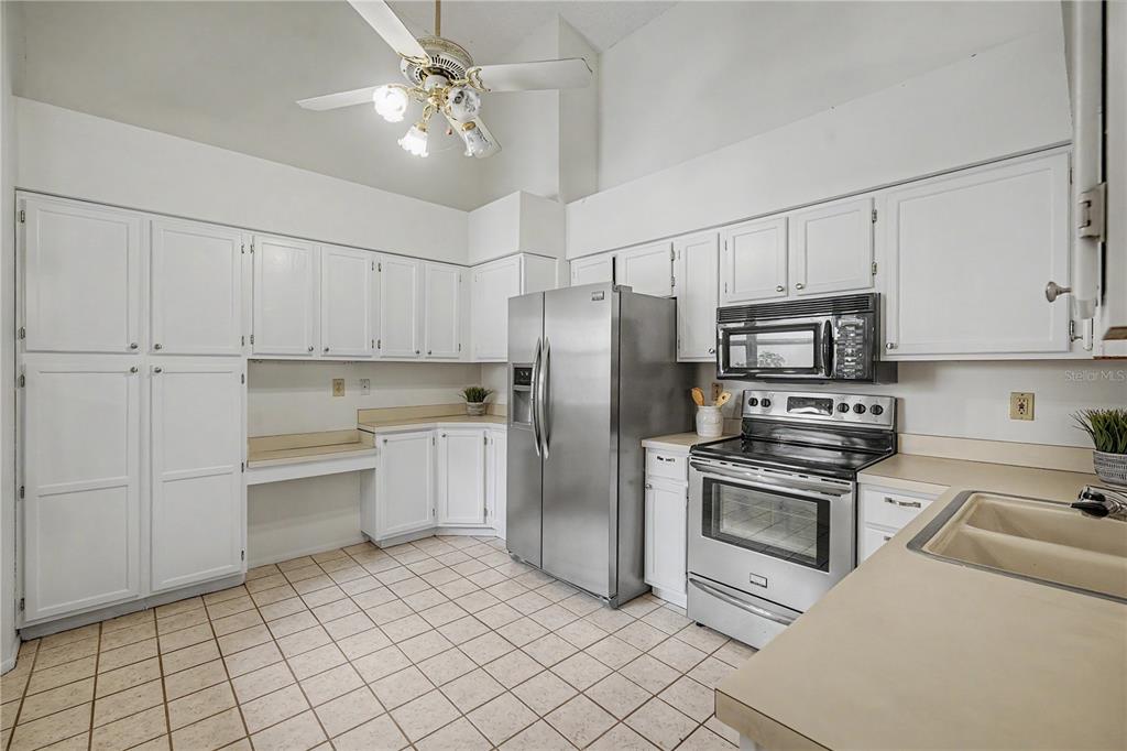 A kitchen with white cabinets, stainless steel appliances, tile flooring, and a ceiling fan — 3960 MERMOOR DRIVE, PALM HARBOR, FL
