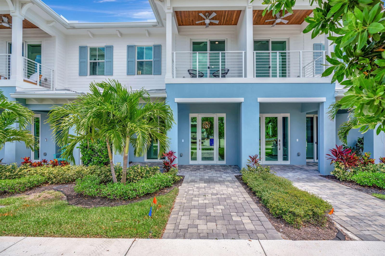 A two-story blue and white building features a paved walkway, palm trees, and upper balconies — 4662 SE Manatee Way, Stuart FL 34997, STUART, FL