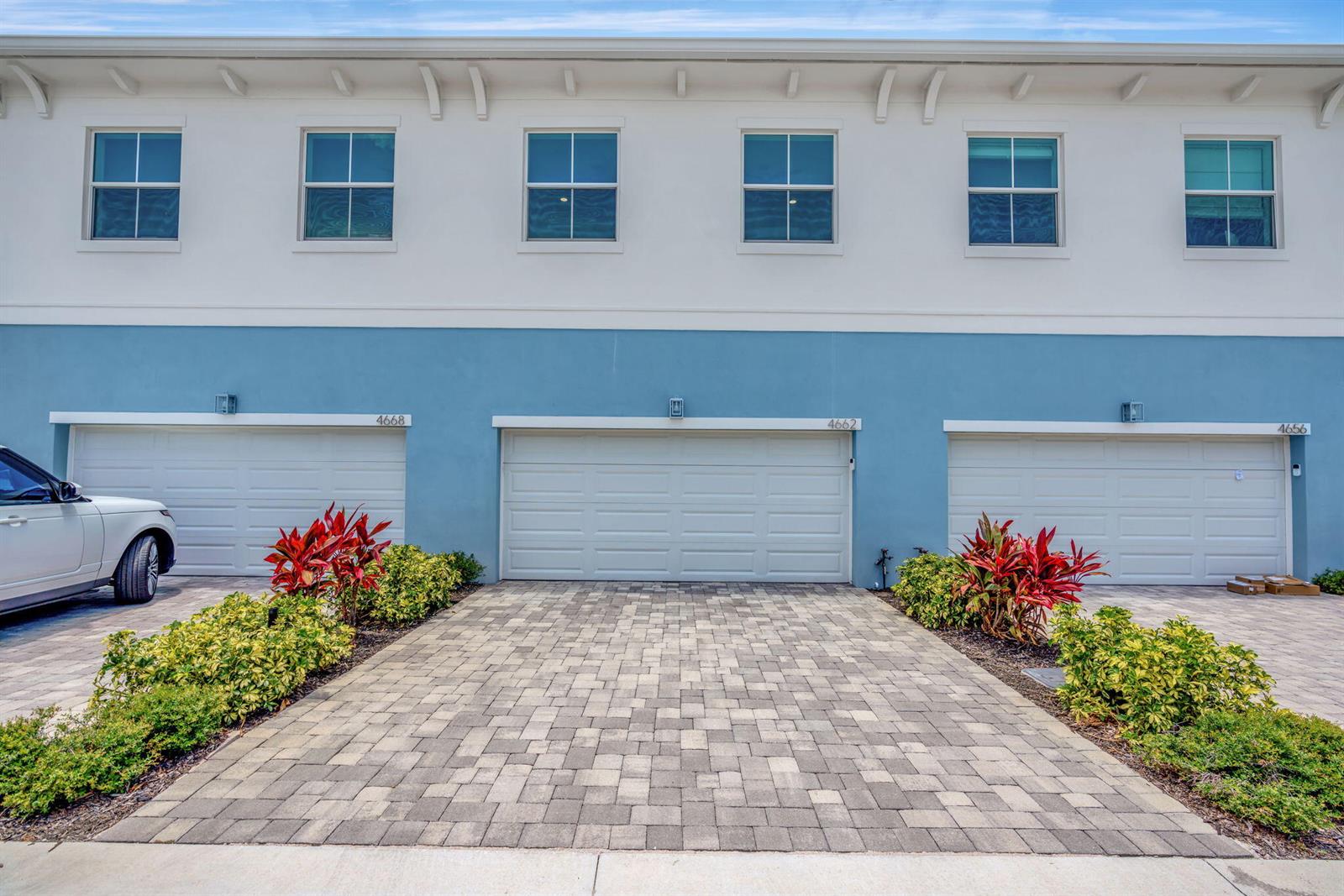 A row of three townhome garages with white doors and blue exterior walls — 4662 SE Manatee Way, Stuart FL 34997, STUART, FL