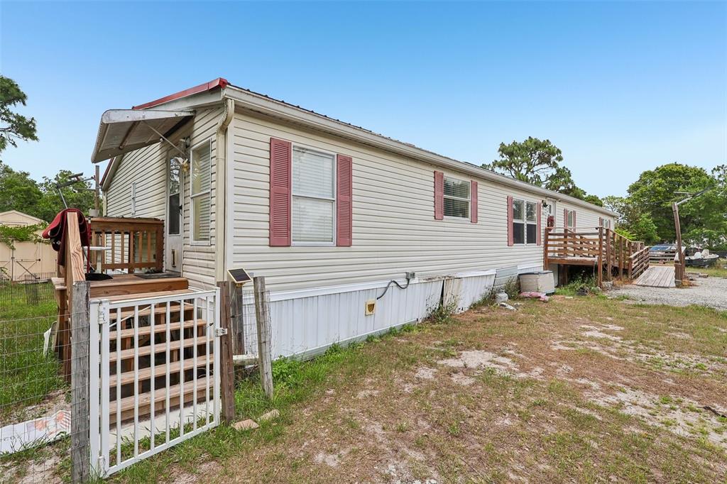 The exterior of a single-wide mobile home features light siding, red shutters, and wooden decks — 9085 MERCURY DRIVE, ST CLOUD, FL