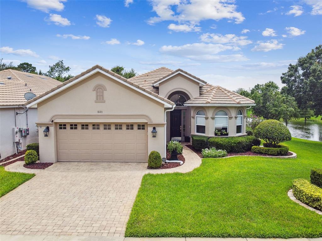 A single-story house with a beige stucco exterior, a two-car garage, and a tiled roof — 521 WESTON PLACE, DEBARY, FL