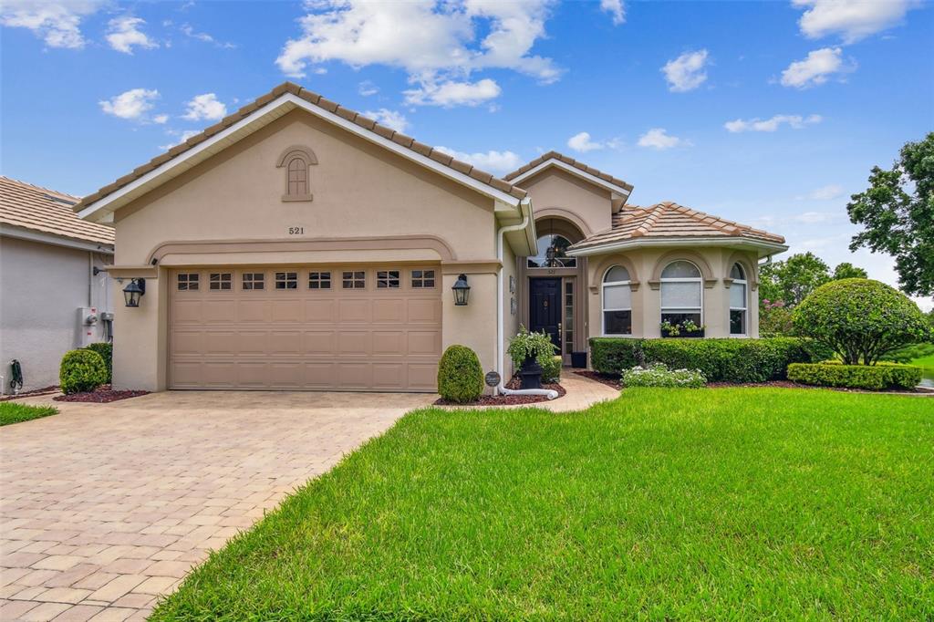 A single-story suburban house features a beige stucco exterior, a two-car garage, and landscaping — 521 WESTON PLACE, DEBARY, FL