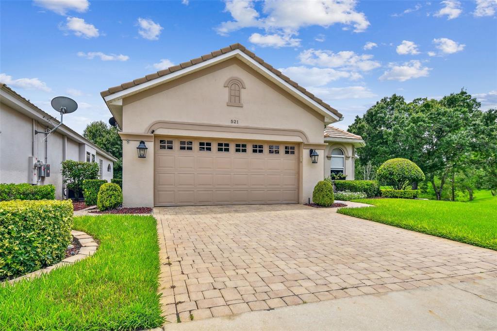 A beige single-story house features a two-car garage and a paved driveway — 521 WESTON PLACE, DEBARY, FL