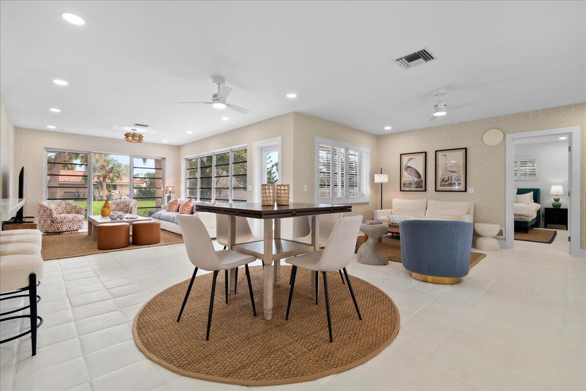An open-concept living and dining area features tile flooring, neutral wallpaper, and large windows — 2412 N Lakeside Drive, FL 33460, FL