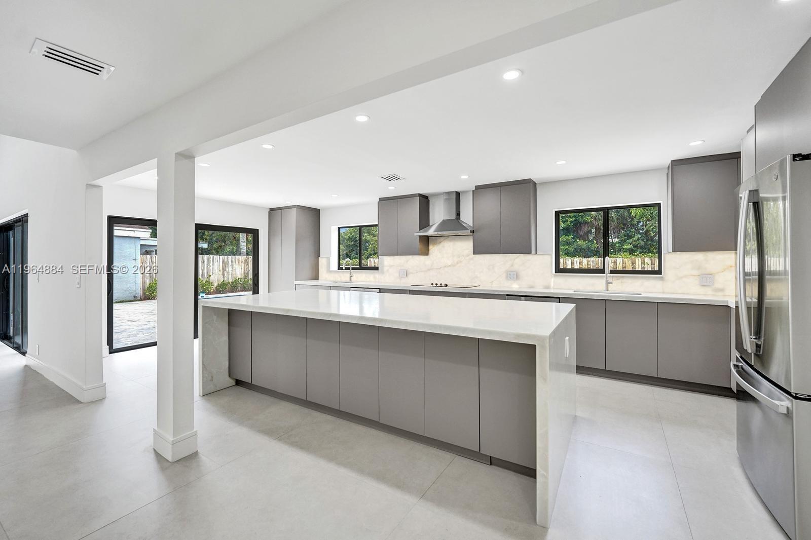 A modern kitchen features gray flat-panel cabinets, a large waterfall island, and white marble countertops — 7340 Andorra Pl, Boca Raton FL 33433, BOCA RATON, FL