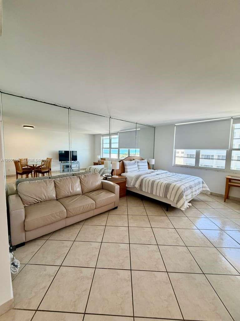 A studio apartment features a bed, a sofa, tiled floors, and a mirrored wall — 100 Lincoln Rd # 731, Miami Beach FL 33139, MIAMI BEACH, FL