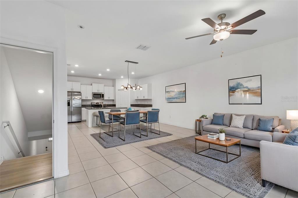 An open-concept living and dining area features tile flooring, a modern kitchen, and neutral furniture — 4706 TUSCAN LOON DRIVE, TAMPA, FL