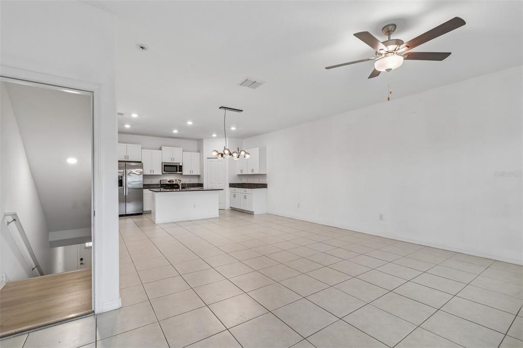 An open-concept kitchen and living area features white cabinetry, stainless steel appliances, and tile flooring — 4706 TUSCAN LOON DRIVE, TAMPA, FL