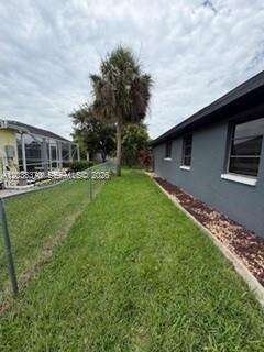 A side yard with a lawn, a palm tree, and a gray house exterior — 209 42nd St., Cape Coral FL 33914, CAPE CORAL, FL