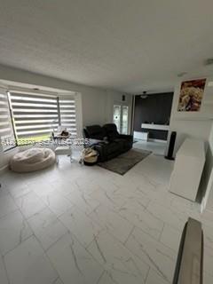 A living room features white marble-style tile flooring, a dark sofa, and large window blinds — 209 42nd St., Cape Coral FL 33914, CAPE CORAL, FL