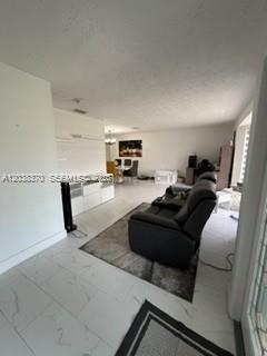 A living room with white tile floors, a dark leather recliner, and a dining area — 209 42nd St., Cape Coral FL 33914, CAPE CORAL, FL