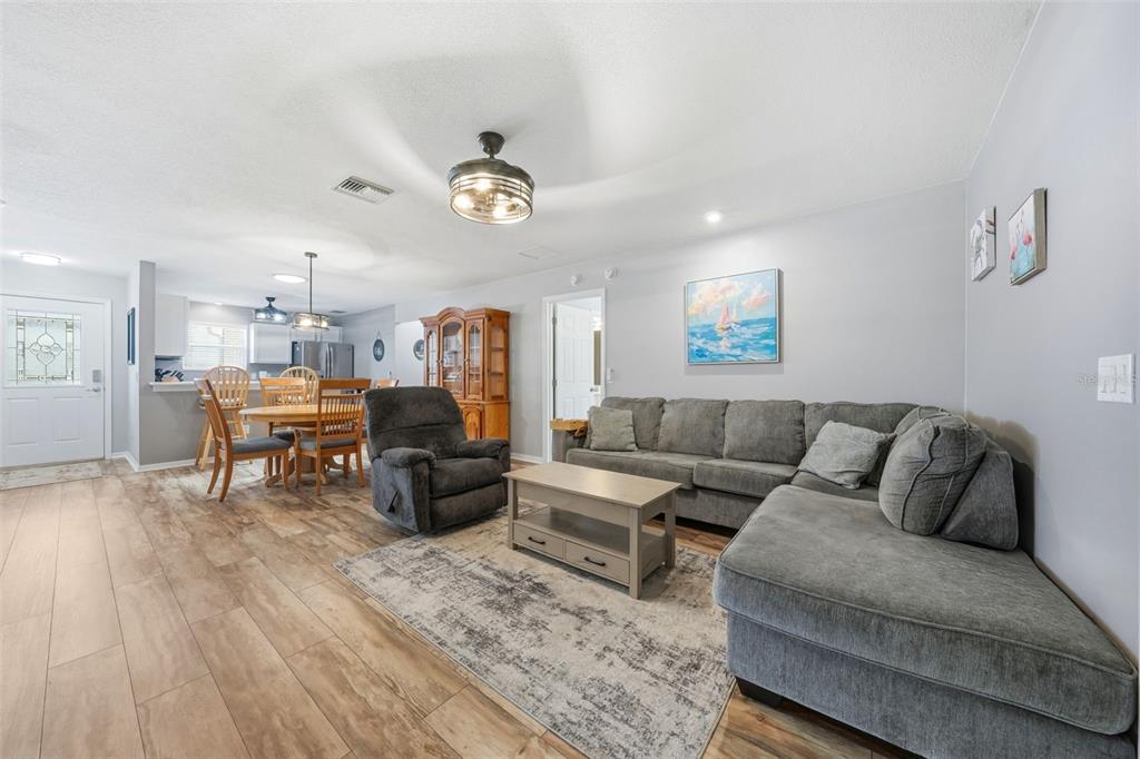 A living room with gray sectional seating, a recliner, and an open-concept dining area — 8142 SE 175TH COLUMBIA PLACE, THE VILLAGES, FL