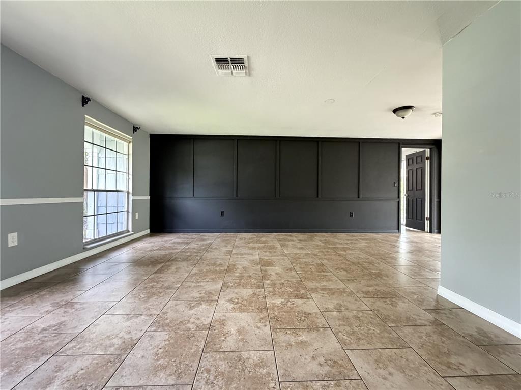 A room with light gray walls, a black paneled accent wall, and tiled flooring — 12407 WEATHERSTONE ROW, HUDSON, FL