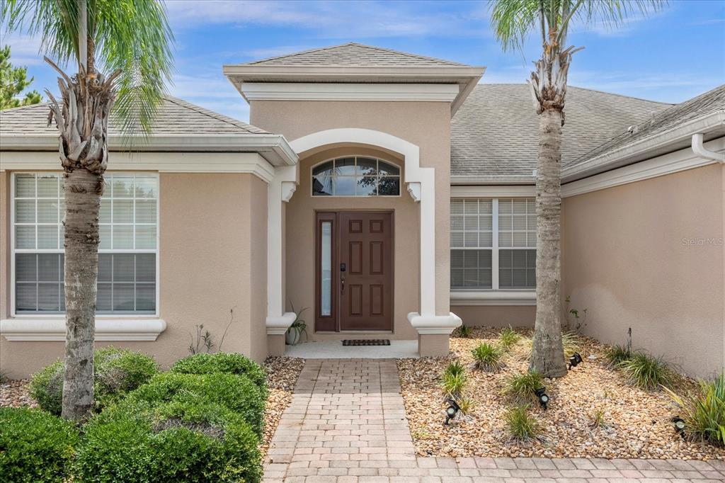 The exterior of a tan house features a brown front door, arched window, and palm trees — 308 YELLOW SNAPDRAGON DRIVE, DAVENPORT, FL