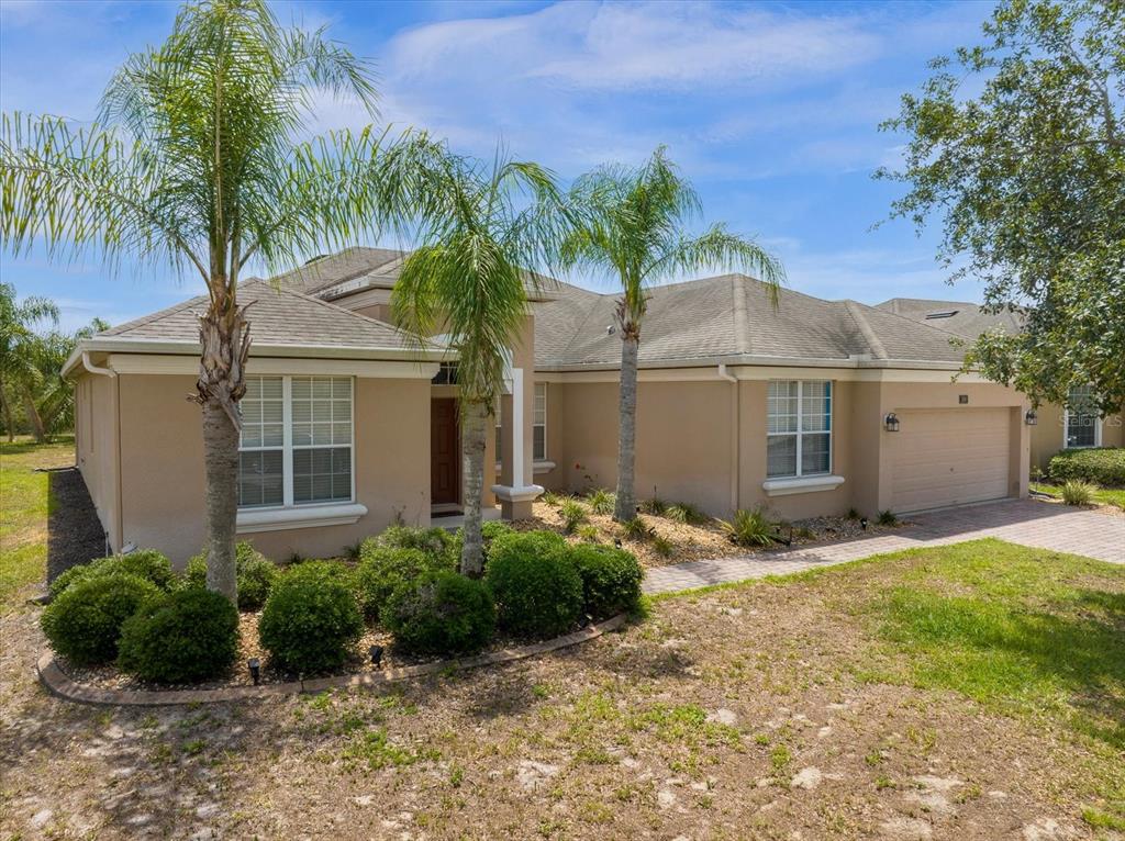 A single-story tan stucco house with a two-car garage and two palm trees in front — 308 YELLOW SNAPDRAGON DRIVE, DAVENPORT, FL