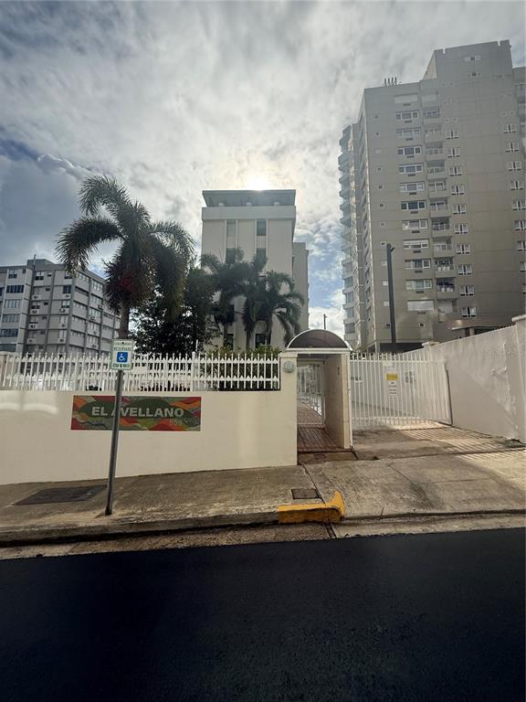 The exterior of a multi-story apartment building features a gated entrance and palm trees — 559 CUEVILLA UNIT 1 B, SAN JUAN, PR