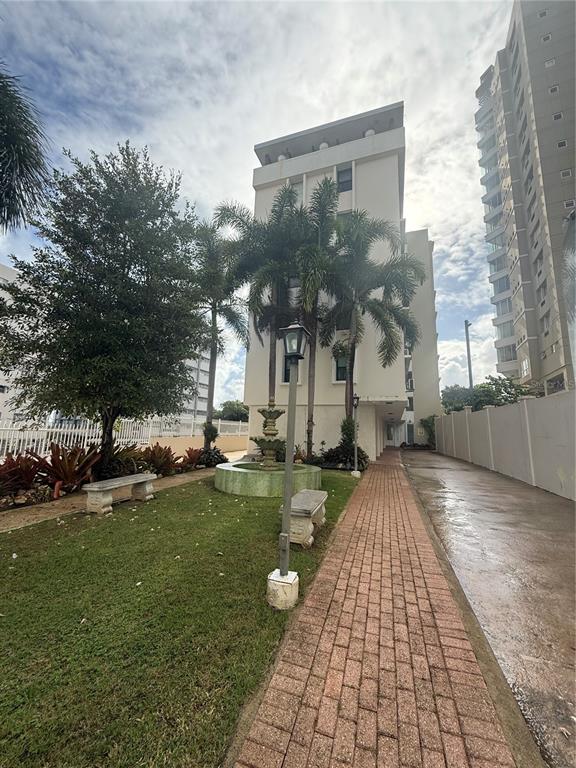 A brick walkway leads toward a multi-story building with a fountain and palm trees — 559 CUEVILLA UNIT 1 B, SAN JUAN, PR