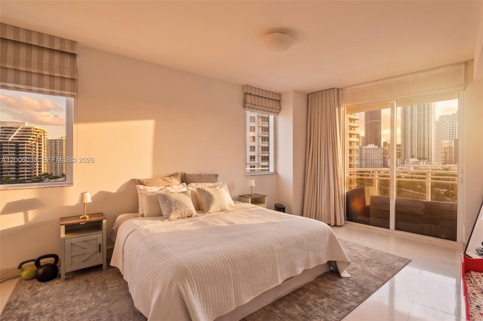 A bedroom features a bed, two nightstands, and floor-to-ceiling windows overlooking a city skyline — 901 Brickell Key Blvd # 1009, Miami FL 33131, MIAMI, FL