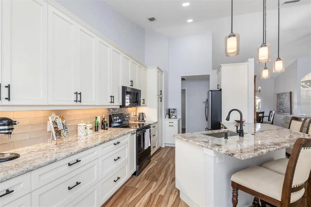 A kitchen features white cabinets, granite countertops, stainless steel appliances, and a central island — 5530 ALMAR DRIVE, PUNTA GORDA, FL