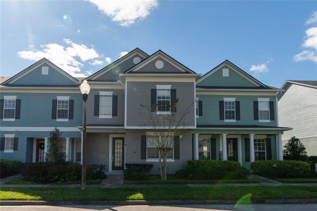 A three-unit townhouse complex features blue and gray siding with white trim and columns — 10224 VICKERS RIDGE DRIVE UNIT 10224, ORLANDO, FL
