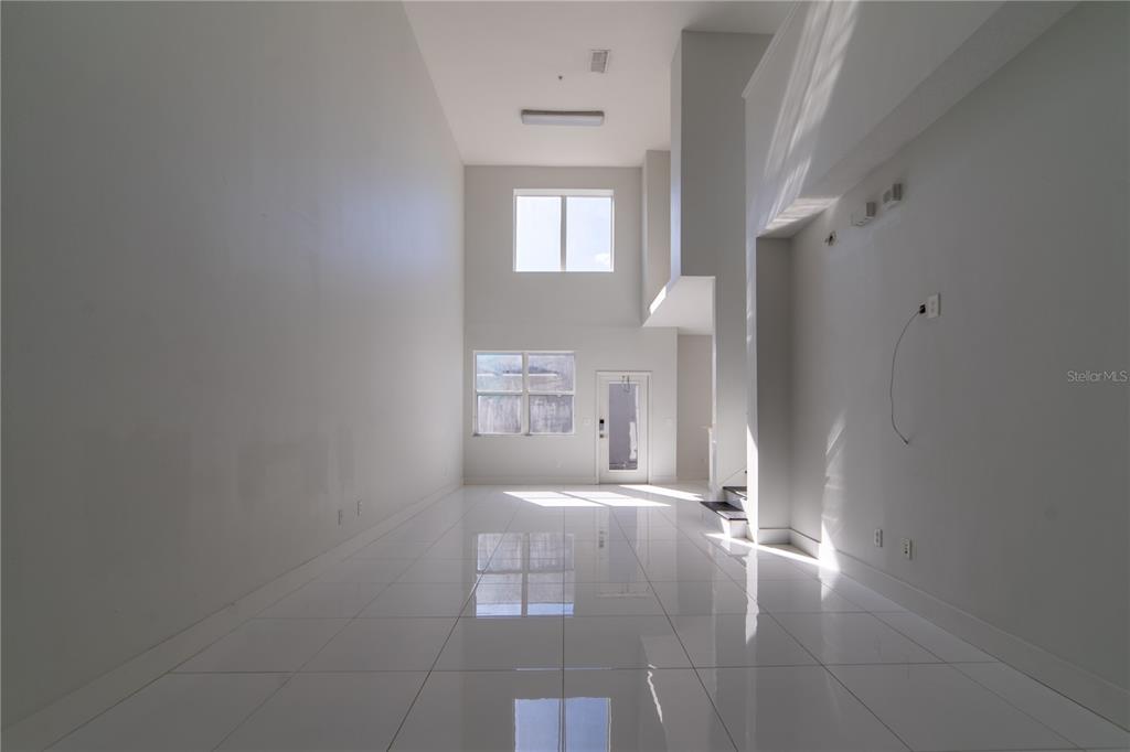 A bright, empty room with high ceilings, white walls, and glossy white tile flooring — 10224 VICKERS RIDGE DRIVE UNIT 10224, ORLANDO, FL