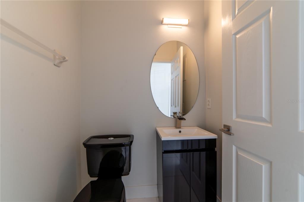 A small bathroom features a black toilet, a black vanity with a white sink, and mirror — 10224 VICKERS RIDGE DRIVE UNIT 10224, ORLANDO, FL