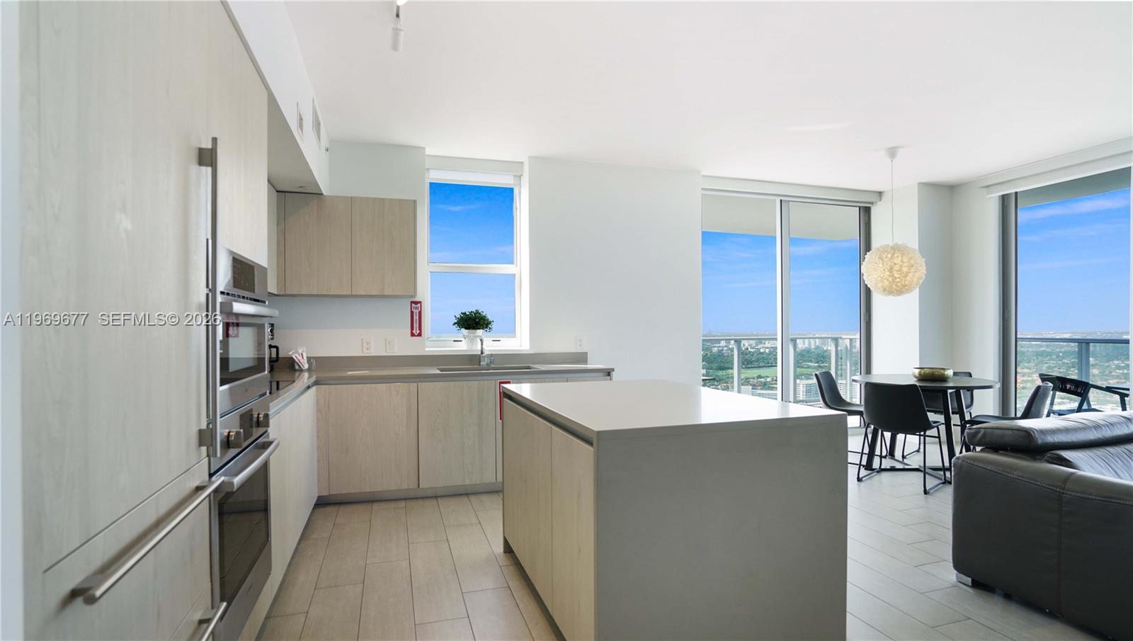 A modern kitchen with light wood cabinets and a central island overlooks a city view — 4010 S Ocean Dr # T4002, Hollywood FL 33019, HOLLYWOOD, FL