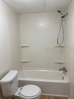 A bathroom features a white toilet and a bathtub with a shower head and surround — 175 PIEDMONT COURT, MELROSE, FL