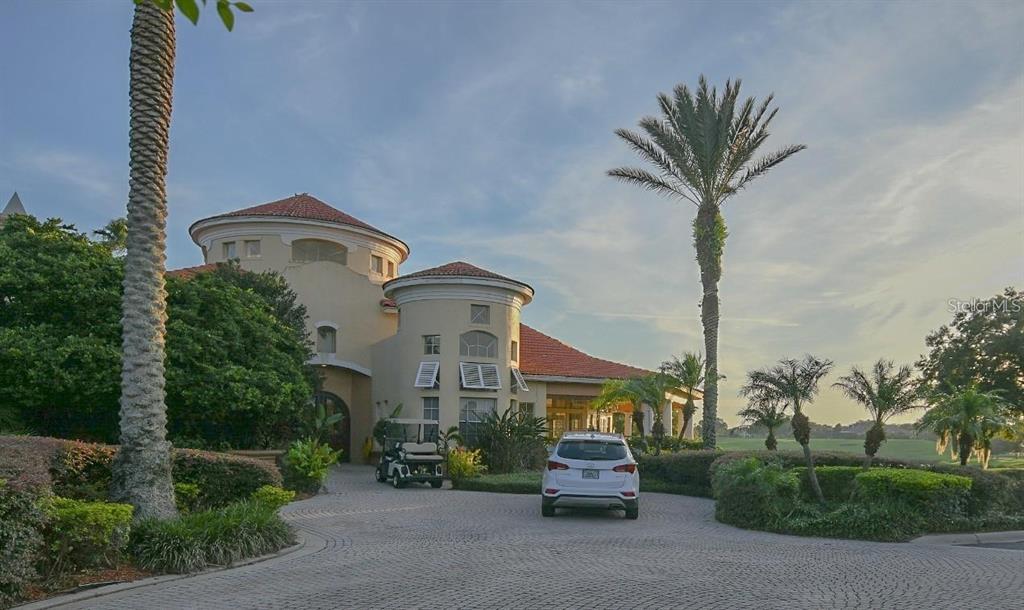 A white SUV sits in the circular driveway of a Mediterranean-style building with palm trees — 7270 WESTPOINTE BOULEVARD UNIT 920, ORLANDO, FL