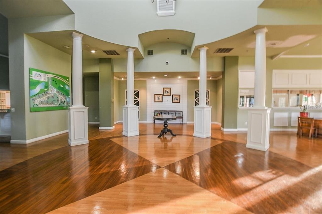 A spacious lobby features hardwood floors, white columns, and a central table with seating — 7270 WESTPOINTE BOULEVARD UNIT 920, ORLANDO, FL