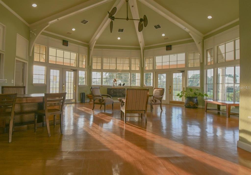 A sunlit room with hardwood floors, vaulted ceilings, and large windows overlooking a green landscape — 7270 WESTPOINTE BOULEVARD UNIT 920, ORLANDO, FL