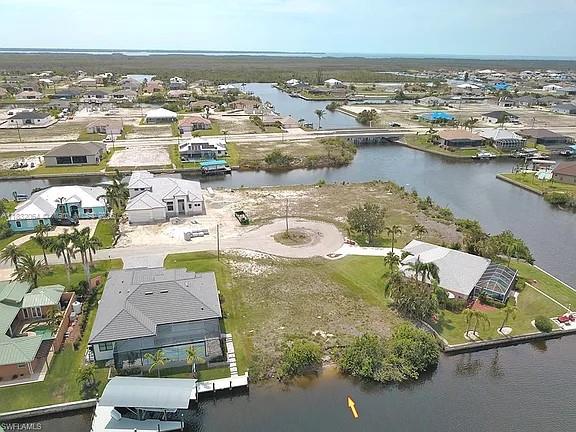 An aerial view shows a vacant waterfront lot surrounded by residential homes and canals — 1253 NW 39th Ave, Cape Coral FL 33993, CAPE CORAL, FL