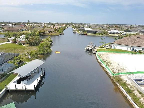 An aerial view shows a canal lined with residential properties, a boat dock, and vacant lots — 1253 NW 39th Ave, Cape Coral FL 33993, CAPE CORAL, FL