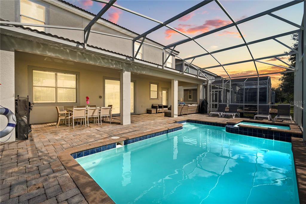 A screened-in patio features a swimming pool, a hot tub, and outdoor dining furniture — 1592 MAIDSTONE COURT, DAVENPORT, FL