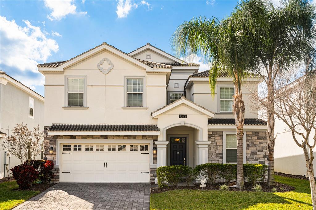 A two-story house with a stone and stucco facade, a two-car garage, and a palm tree — 1592 MAIDSTONE COURT, DAVENPORT, FL