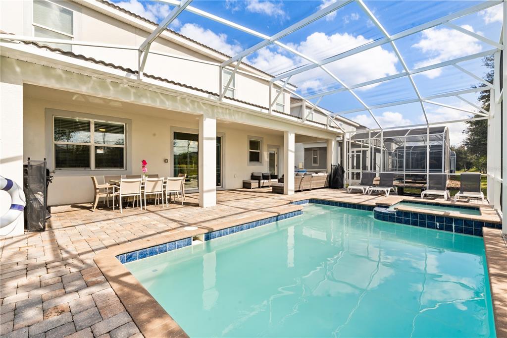 A screened-in patio features a swimming pool, a hot tub, and an outdoor dining area — 1592 MAIDSTONE COURT, DAVENPORT, FL