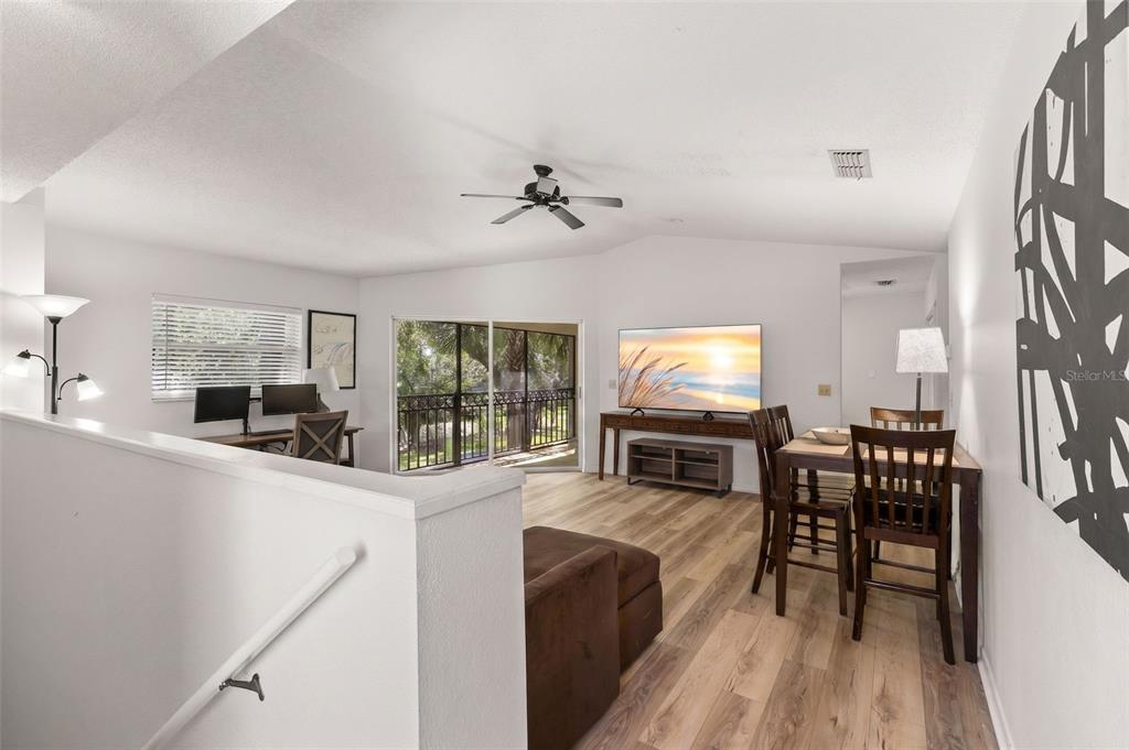 A living and dining area features wood-look flooring, a ceiling fan, and a sliding glass door — 500 SANTA CRUZ PLACE NE UNIT F, ST PETERSBURG, FL