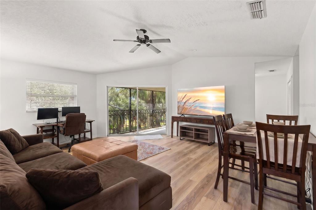A living room with a brown sectional, dining area, desk, and sliding glass doors to a balcony — 500 SANTA CRUZ PLACE NE UNIT F, ST PETERSBURG, FL