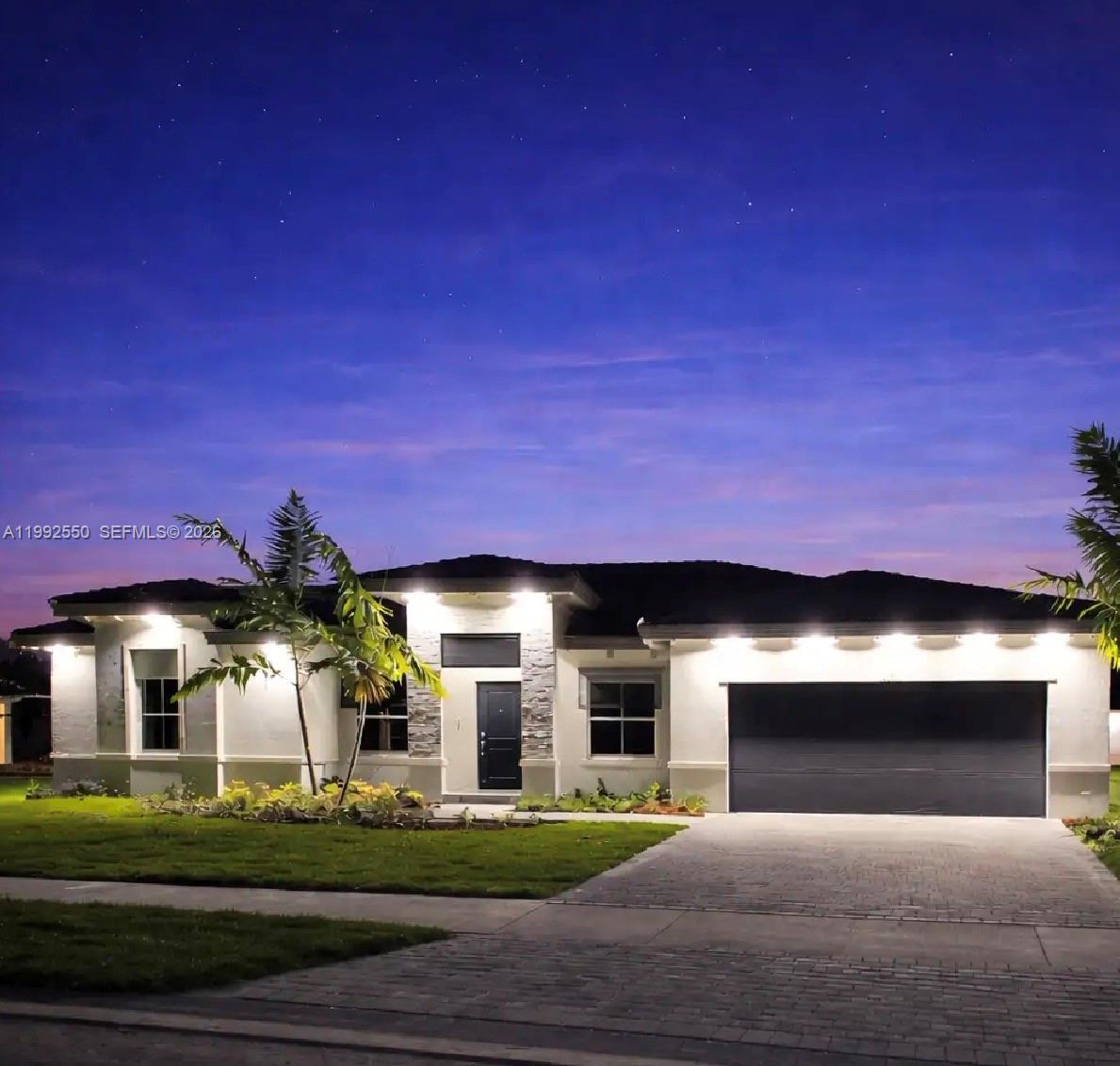 A single-story house with a stone-accented entryway, dark garage door, and exterior soffit lighting — 19303 SW 132nd Path, Miami FL 33177, MIAMI, FL