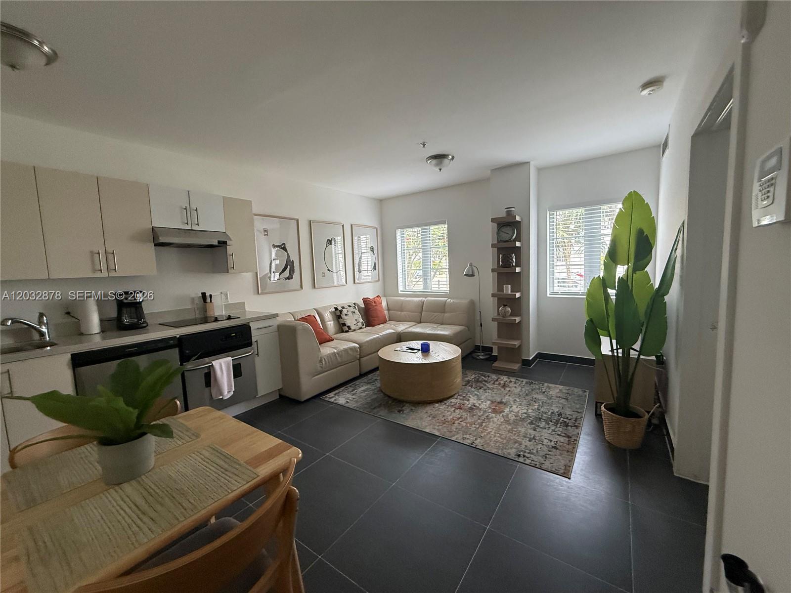 An open-concept living area features a kitchen, dining table, and sectional sofa on tile floors — 1600 Euclid Ave # 102, Miami Beach FL 33139, MIAMI BEACH, FL
