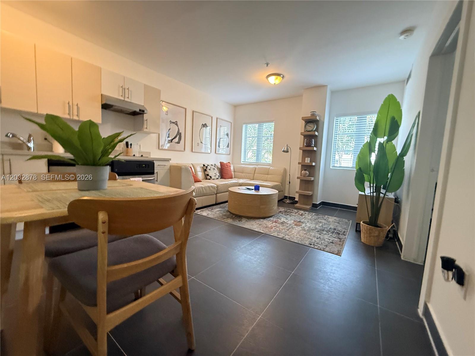 An open-concept living and dining area features tile flooring, light cabinetry, and a sectional sofa — 1600 Euclid Ave # 102, Miami Beach FL 33139, MIAMI BEACH, FL