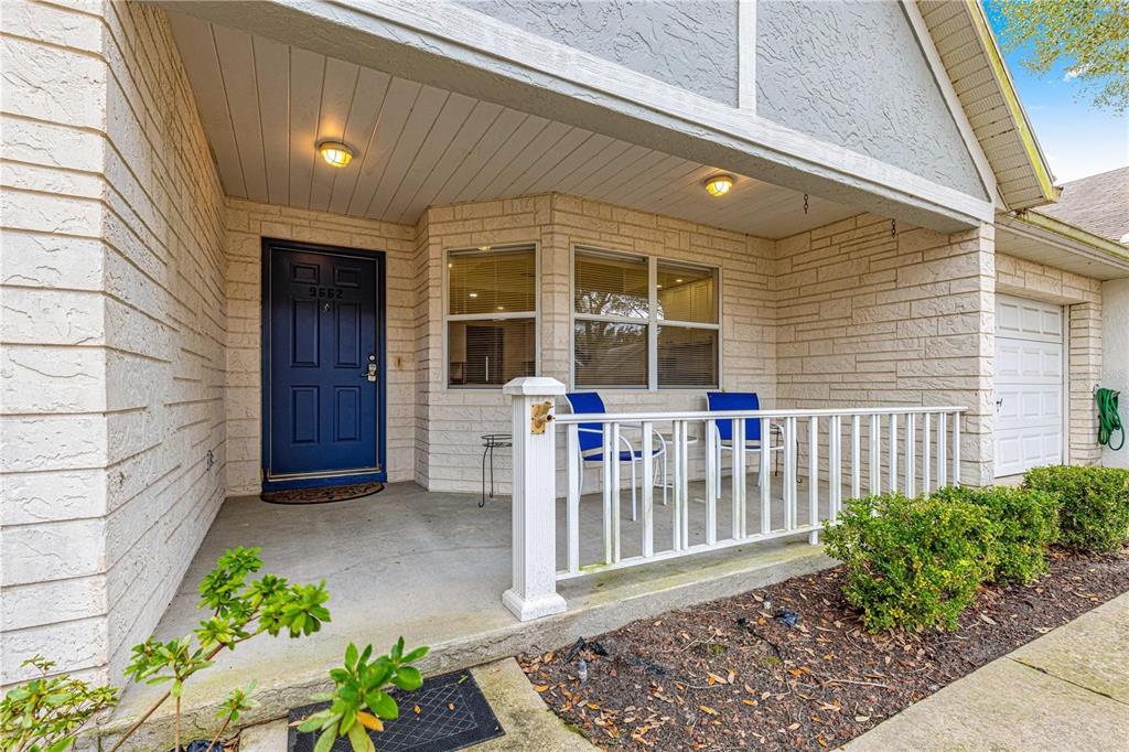 A covered front porch features a blue door, white railing, and two blue chairs — 9662 SW 95TH COURT UNIT A, OCALA, FL