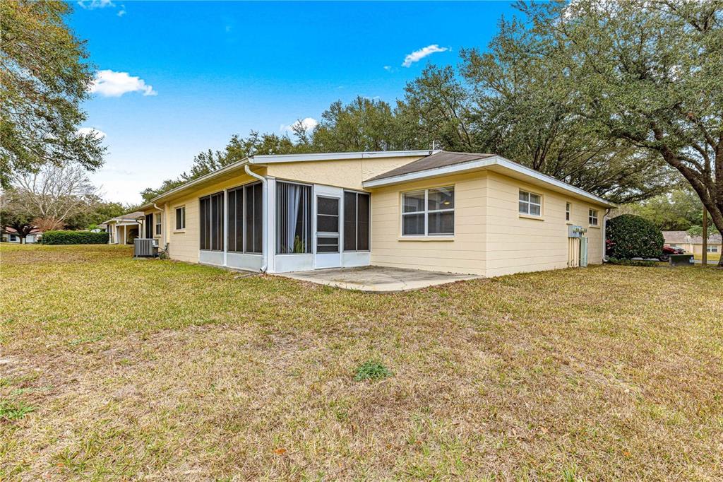 The exterior of a yellow house features a screened-in porch and a concrete patio — 9662 SW 95TH COURT UNIT A, OCALA, FL
