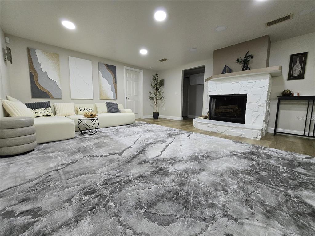 A living room features a white stone fireplace, a large sectional sofa, and marble-patterned carpeting — 2625 HARRIS BOULEVARD, KISSIMMEE, FL