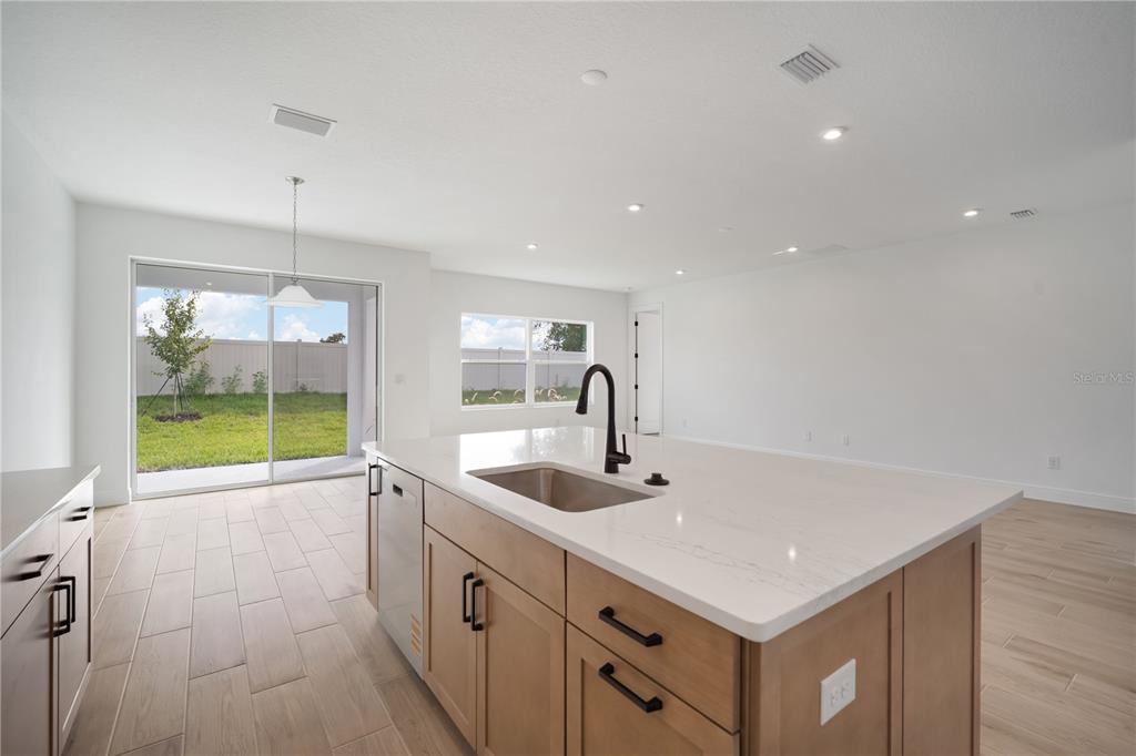 A kitchen island with a sink and light wood cabinets sits in a bright room — 2951 STEWART CREEK CIRCLE, PLANT CITY, FL