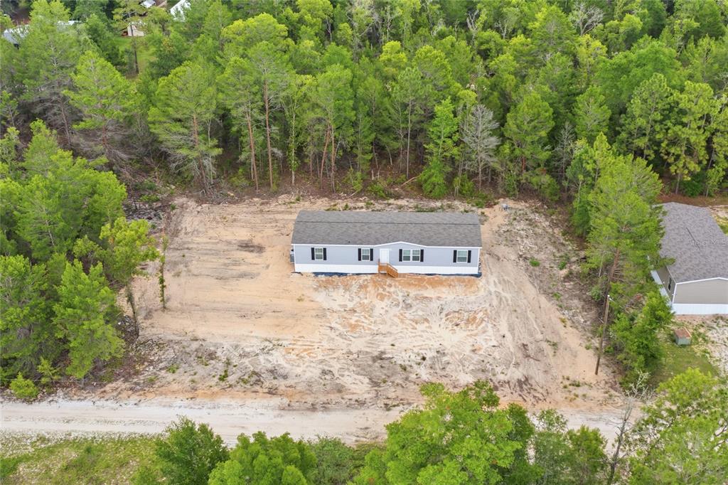 An aerial view shows a single-story manufactured home situated on a cleared, sandy lot — 150 19TH STREET, INTERLACHEN, FL