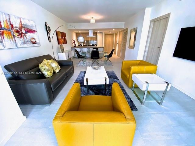 A living room features a dark leather sofa, yellow armchairs, and a white coffee table — 1000 Brickell Plaza # 1914, Miami FL 33131, MIAMI, FL