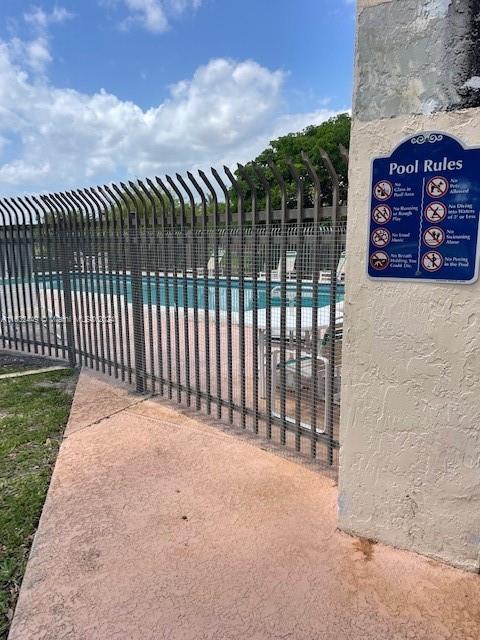 A swimming pool is enclosed by a metal fence next to a pool rules sign — 10145 NW 9th St Cir # 502, Miami FL 33172, MIAMI, FL